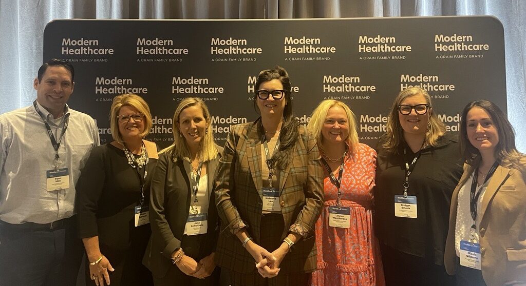 Floyd Lee Locums representatives standing in front of Modern Healthcare banner